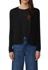 Zwarte cardigan met een open voorkant, lange mouwen en zachte stof, gecombineerd met een donkere top en lichtblauwe wijde jeans.