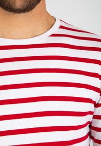 T-shirt a righe rosse e bianche in cotone, con colletto a girocollo e righe orizzontali uniformi sul petto e sulle spalle.