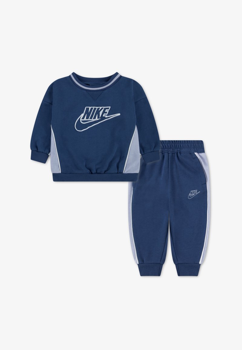 Marineblauw Nike trainingspak met contrasterende lichtblauwe zijpanelen. Sweatshirt met ronde hals en logo; broek met elastische tailleband en boorden.