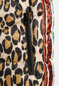 Chaqueta acolchada con estampado de leopardo, con un cierre negro, textura brillante y acentos de rayas coloridas en rojo, azul y amarillo.