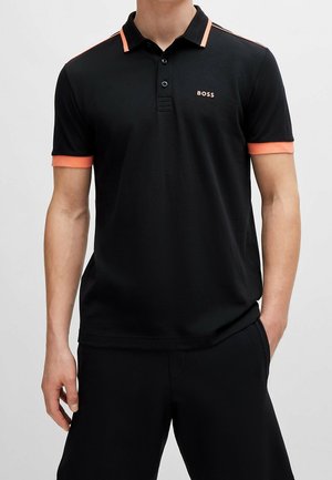 Homme portant un polo noir avec un liseré orange sur le col, les manches et les épaules, avec le logo "BOSS" sur la poitrine gauche.
