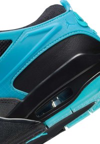 En närbild på en sneaker med en svart och turkos design, med ovandel i texturerat material och en genomskinlig svart sula och detaljer.