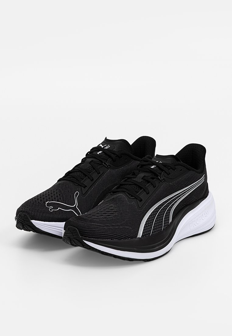 Scarpe da ginnastica nere con tomaia in rete testurizzata, chiusura con lacci e suola intermedia bianca. Presentano un logo PUMA argentato e un design aerodinamico.