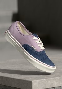 Vans sneakers with a lavender canvas upper and navy suede accents. Features white laces and a rubber sole with red heel accent.