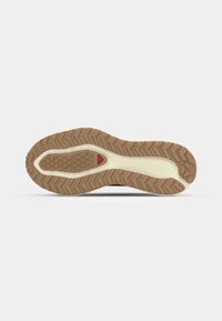 Sport shoe sole featuring a textured gum rubber outsole with a zigzag pattern, a cushioned midsole, and a red accent near the heel.