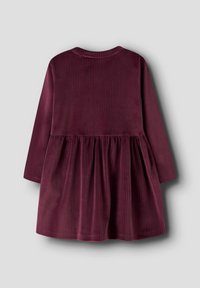 Viininpunainen korduroi mekko, jossa on pitkät hihat, pyöreä kaula-aukko ja kerätty hame. Vaakasuuntainen ribbettekstuuri koko kankaan läpi.