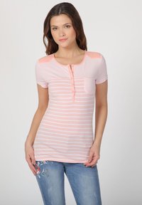 Top corto de manga corta rosa claro con rayas horizontales blancas, escote redondo, tapeta de botones y un pequeño bolsillo en el pecho. Textura de tela suave.