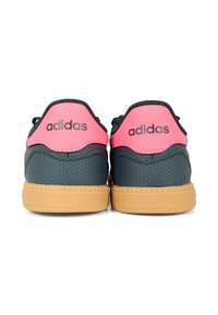 Basket Adidas avec une tige en cuir bleu foncé, des accents roses au talon et une semelle en caoutchouc beige, présentant une texture perforée.