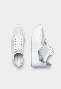 Sneakers bianchi con accenti argento, realizzati in materiali misti di rete testurizzata e pelle, punta arrotondata e suola piatta in gomma. Lacci con occhielli metallici.