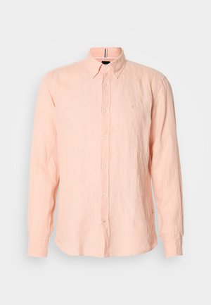 Chemise à manches longues rose clair à boutons, avec un col à rabat et un petit logo brodé sur la poitrine gauche.