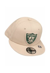 Cappellino snapback beige con patch del logo verde dei Raiders sul davanti, con visiera piatta e tessuto testurizzato.