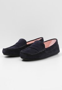 Mocassins en suède bleu marine avec un design cousu, dotés d'un bout moccasin, d'accents de couture surélevés et d'une doublure intérieure douce de couleur rose clair.