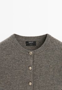 Cardigan grigio in lana con scollatura arrotondata, chiusura a bottoni con dettagli metallici e una finitura morbida e testurizzata.