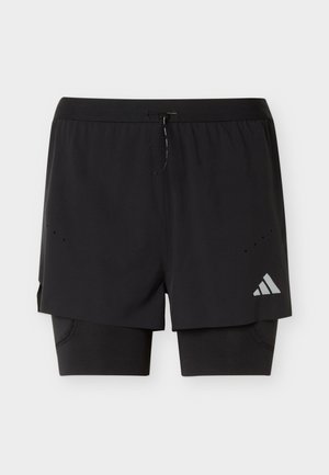 Shorts de sport noirs deux-en-un avec couche de compression intérieure, taille avec cordon, petits trous de ventilation et logo réfléchissant sur la jambe droite.