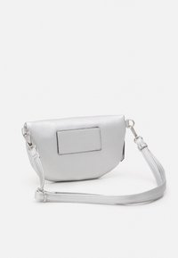 Srebrna skórzana torebka na ramię o zaokrąglonym kształcie, z płaską przednią kieszenią i odczepianym paskiem. Charakteryzuje się gładką teksturą i minimalistycznym designem.