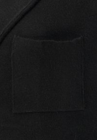 Tessuto nero con una finitura texture che presenta una tasca rettangolare. Il materiale appare morbido e leggermente peloso.