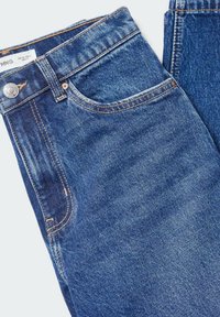 Jean en denim bleu plié, montrant la poche avant, le bouton métallique, la boucle de ceinture et les détails de couture visibles.
