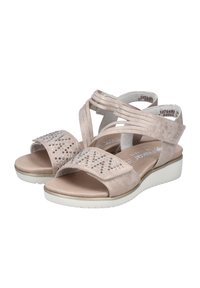 Beige sandals featuring a soft fabric upper with multiple straps, a textured footbed, and decorative rhinestones on the front strap.