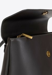 Czarna skórzana torebka o gładkiej teksturze. Posiada złoty zamek błyskawiczny z wygrawerowanym napisem "WITTCHEN" oraz okrągłe złote zapięcie na zatrzask wewnątrz.