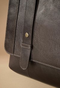 Dark brown leather bag with a textured surface, featuring a folded flap, stitched accents, and a metal snap closure.