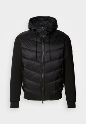 Black jacket with a puffy quilted front and soft fabric sleeves. Features a hood, full zipper, and side pockets.