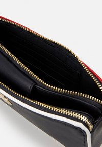 Black leather wallet with a red trim, gold zipper, and white accent. Interior features card slots and fabric lining. Zippered compartments included.