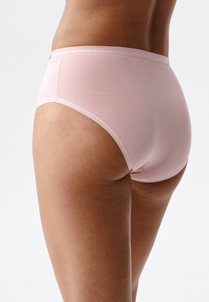 Kobieta w jasnoróżowej bawełnianej bieliźnie z wysokim stanem, pokazana od tyłu na jednolitym białym tle.