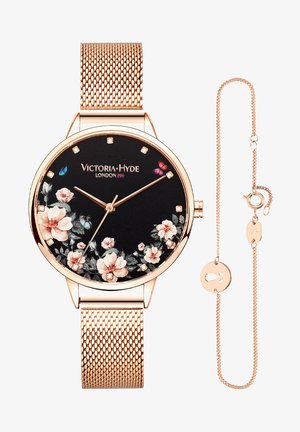 Okrugli crni sat s cvjetnim dizajnom i ružičastim zlatnim akcentima. Metalna mrežasta narukvica. Uključuje delikatnu usklađenu narukvicu s privjeskom.