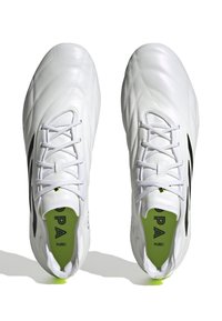Scarpini da calcio bianchi con accenti neri, tomaia in sintetico liscio, lati testurizzati, design con lacci e soletta verde brillante.