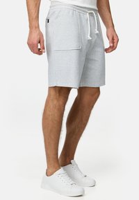 Shorts bleu clair texturé avec une taille élastique et un cordon de serrage, dotés de poches latérales. Portés avec des baskets blanches.