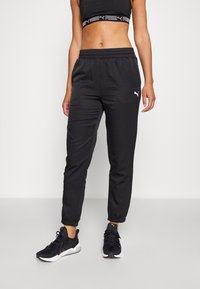 Pantaloni sportivi neri con vita elastica e polsini affusolati. Presentano un logo Puma bianco all'altezza dell'anca. Tessuto liscio e leggero.