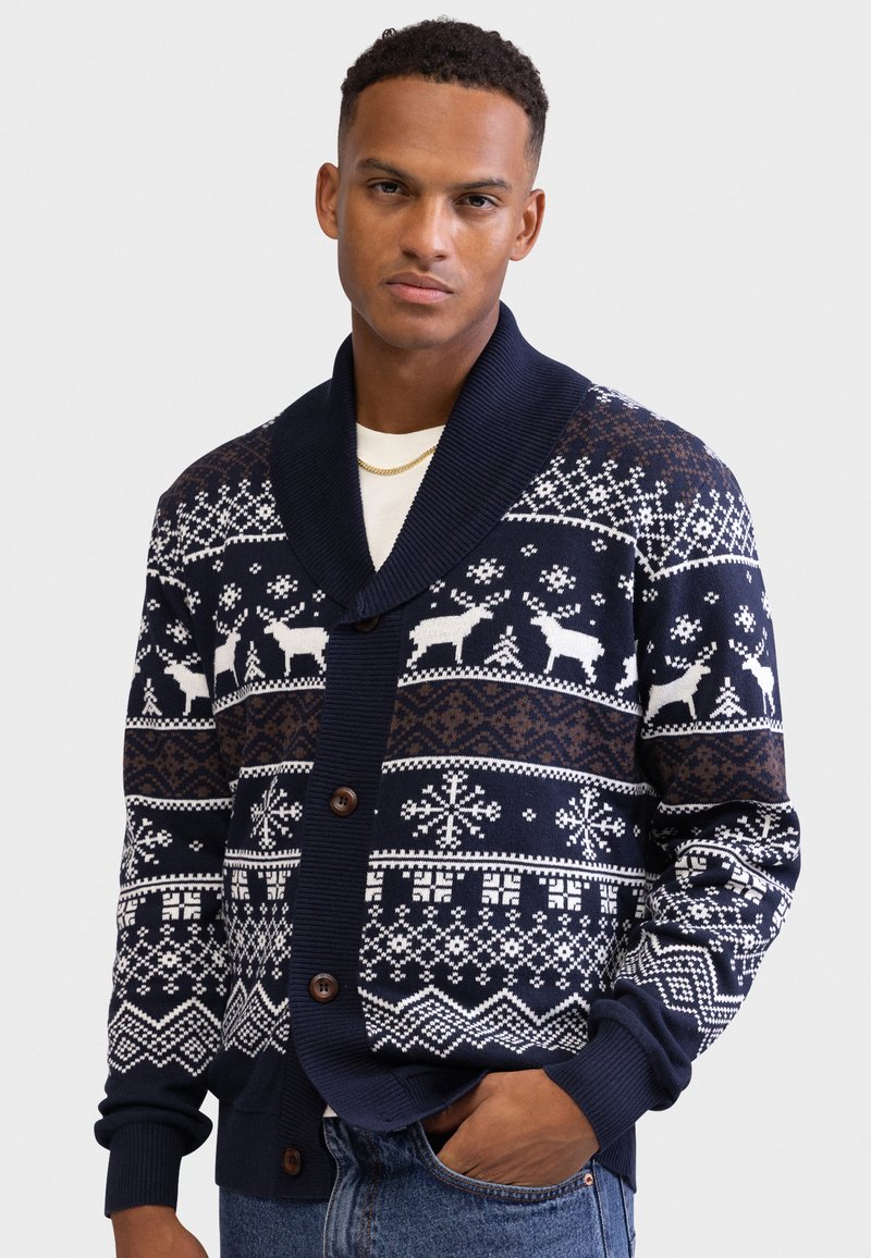 Cardigan tricotat bleu marin cu guler șal, decorat cu modele geometrice și reni în alb și maro, și cu nasturi din lemn.