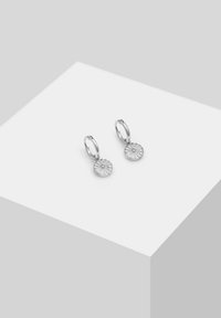 Pendientes de aro de plata con un colgante redondo y texturizado que presenta un patrón radiante. El diseño enfatiza la simplicidad y la elegancia.