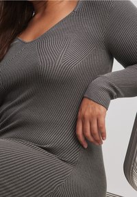 Abito a costine grigio con scollatura a V e maniche lunghe, caratterizzato da una sottile trama e dettagli di contorno lungo il corpo.