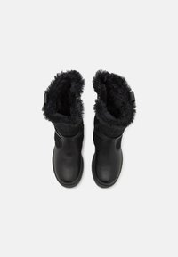 Bottes en cuir noir avec une douce doublure en fourrure noire en haut, présentant une surface lisse et un design à bout rond.