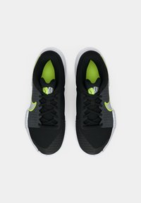 Μαύρα αθλητικά παπούτσια με υφή από διχτυωτό ύφασμα και συνθετικές επικαλύψεις, με φωτεινές πράσινες λεπτομέρειες και λευκή σόλα. Σχέδιο με κορδόνια, χαμηλό προφίλ.