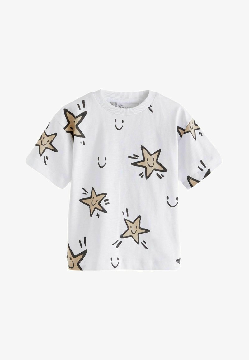 Fehér, rövid ujjú póló, bézs színű mosolygó csillagok fekete körvonalaival és szórványos mosolygós fejekkel, puha pamut anyagból készült.