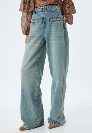 Jean large bleu clair en denim avec une finition délavée, comportant deux poches avant et des accents de couture aux coutures.