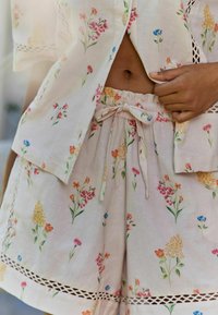 Lightweight, floral-patterned cotton blouse and shorts set. Features pastel colors, elastic waistband, and lace accents along hems.