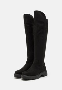 Black knee-high boots made of soft suede, featuring a rounded toe, elastic side panels, and a textured rubber sole. Smooth finish and minimal design.