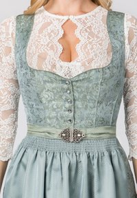 Traditionelles Kleid mit einem blumenmusternden, hellgrünen Oberteil, Spitzenärmeln, einem plissierten Rock und einer dekorativen Gürtelschnalle in Silberoptik.