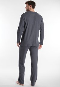 Top grigio a maniche lunghe e pantaloni abbinati in una texture a coste, caratterizzati da una vestibilità rilassata e dettagli di cucitura sottili.