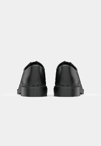 Black leather shoes with a smooth finish, rounded toe, and textured rubber sole. Features minimal design and no visible hardware.