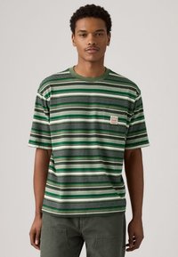 Camiseta de rayas verdes con mangas cortas, con líneas horizontales en diferentes tonos de verde y negro, y un pequeño logo en el bolsillo del pecho.