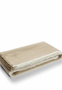 Beige tæppe med en blød tekstur, der har en frynset kant og lys cremefarvet trim. Inkluderer en subtil broderet logodetalje.
