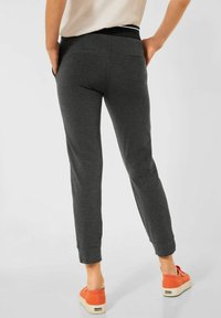 Grå sweatpants med en avsmalnande passform och elastisk midja. Tyget är mjukt med bakfickor, i kombination med orange skor.