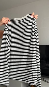 Black and white striped long-sleeve shirt with a rounded neckline. Made from a smooth fabric, featuring even horizontal stripes and a relaxed fit.