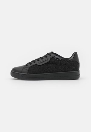 Baskets basses tout-noir avec design à lacets, panneaux latéraux en tissu texturé présentant un motif répété "MK", et accents lisses à l'avant et au talon.