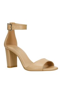 Beige High Heels Sandalen mit einem breiten Zehenriemen, offenem Fersenbereich und verstellbarem Knöchelriemen mit einer metalischen Schnalle. Glattes Lederdesign.
