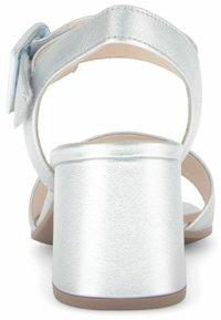 Sandal in metallo argento con tacco a blocco, cinturino alla caviglia e design aperto sul retro; texture liscia e linee minimaliste e pulite.